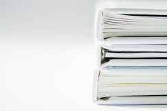 A stack of thick folders on a white surface.