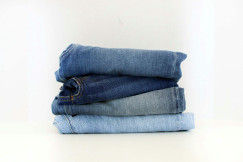 Stack of folded blue jeans in different denim washes, ranging from light to dark blue