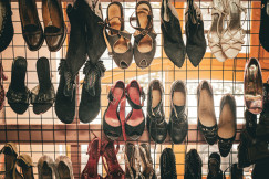Various styles of women's footwear, including boots, sandals, heels and leather shoes, displayed on a metal rack in a retail setting.