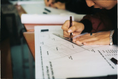 This picture appears to show a close-up of a person working on a technical drawing or architectural/engineering plan at a desk.