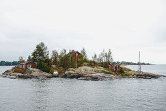 The photo presents a small rocky island with red houses.