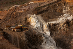 The photo presents an open-pit mining site with heavy machinery.