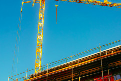 This picture shows an active construction site viewed from a low angle against a clear blue sky.