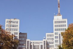 The picture shows the front exterior of a large multi-storey institutional or office building, photographed from an open paved area.