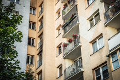 The picture shows the exterior of a multi-storey residential apartment building, viewed upward from a courtyard or the space between buildings.