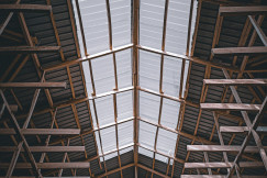 This picture shows the interior roof structure of a large industrial or agricultural building, photographed looking upward.