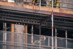 The picture shows construction workers carrying out building work on an elevated level of an active construction site.