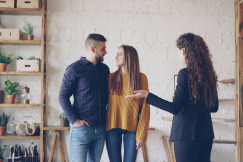 The picture shows an indoor property viewing or consultation, with three people standing in a bright, modern interior.