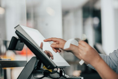 The photo presents a person using a touchscreen payment terminal.