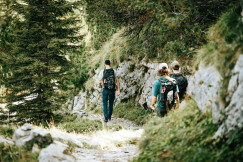 The photo presents hikers walking on a mountain trail.