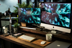 Colour photograph of two computer monitors turned on with the same wallpaper