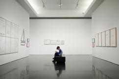 An illustrative photo of a man sitting near a painting in a museum