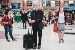 An illustrative photo of a man standing and holding his luggage bag