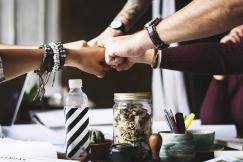 An illustrative photo of a group of people join hands in a collaborative gesture