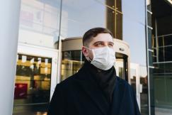 An illustrative photo of a man in a mask outside his office 
