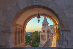 An illustrative photo of a view through a stone archway during sunset or sunrise.