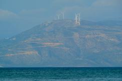 An illustrative photo of a white sailboat gliding on the sea near a mountain