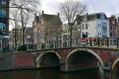 An illustrative photo of a bridge over a river with buildings in the background