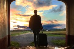 An illustrative photo of a man holding luggage, ready for his journey