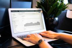 An illustrative photo of a person using a laptop with statistical data on the screen