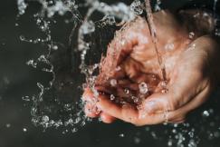 An illustrative photo of a person holding their hands under a stream of water.