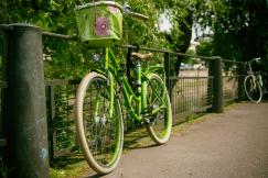 An illustrative photo of a green cruiser bike with a basket leaning on a gray rail