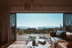 An illustrative photo of a modern living room with a view of the sea through large glass windows.