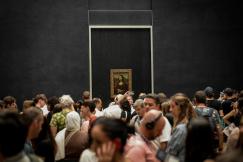 An illustrative photo of a crowd of visitors viewing the Mona Lisa painting at the Louvre