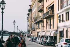 An illustrative photo of People walking along a bustling pavement beside a grand, historic building