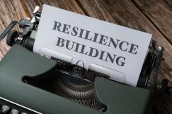 An illustrative photo of a typewriter with a sheet of paper that has the words “resilience building” typed on it