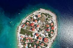 An illustrative photo of a small island with red-roofed buildings, surrounded by blue waters