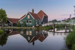 An illustrative photo of a green house beside body of water.
