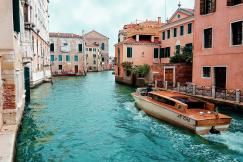 An illustrative photo of a view of a canal in Venice, Italy, with a boat moving through the water. 