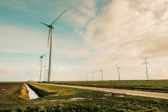 An illustrative photo of windmills standing on a green grass field.