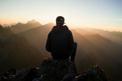 An illustrative photo of a man sitting on the mountain edge.