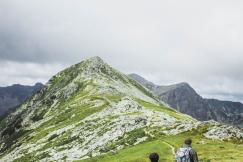An illustrative photo of two people walking on a hill under white clouds