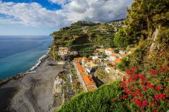 An illustrative photo of houses on the coast with mountains behind them