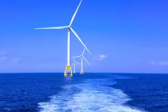 An illustrative photo of three white wind turbines standing in the sea