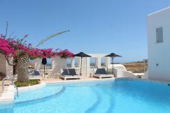 An illustrative photo of a white and brown concrete house near swimming pool.