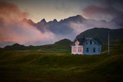 An illustrative photo of a white and gray house near mountain.