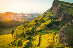 An illustrative photo of a green hill with winding paths, set against a backdrop of a cityscape.