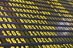 An illustrative photo of an airport departure board displaying various destination cities