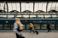 An illustrative photo of people walking on sidewalk near train.