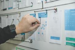 An illustrative photo of a person working on a blue and white paper on a board