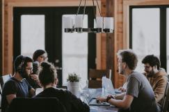 An illustrative photo of people sitting beside a table inside a room
