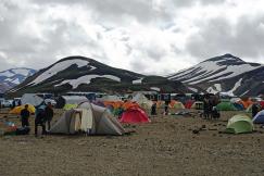 An illustrative photo of a bustling campsite with numerous colorful tents set up on a gravelly terrain