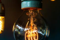 An illustrative photo of an illuminated incandescent light bulb with a visible filament