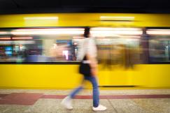 An illustrative photo of a person walking in front of a yellow train