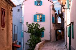 An illustrative photo of a narrow street between white concrete houses