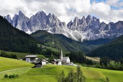 An illustrative photo of a a landscape with mountains in the background under a partly cloudy sky. 